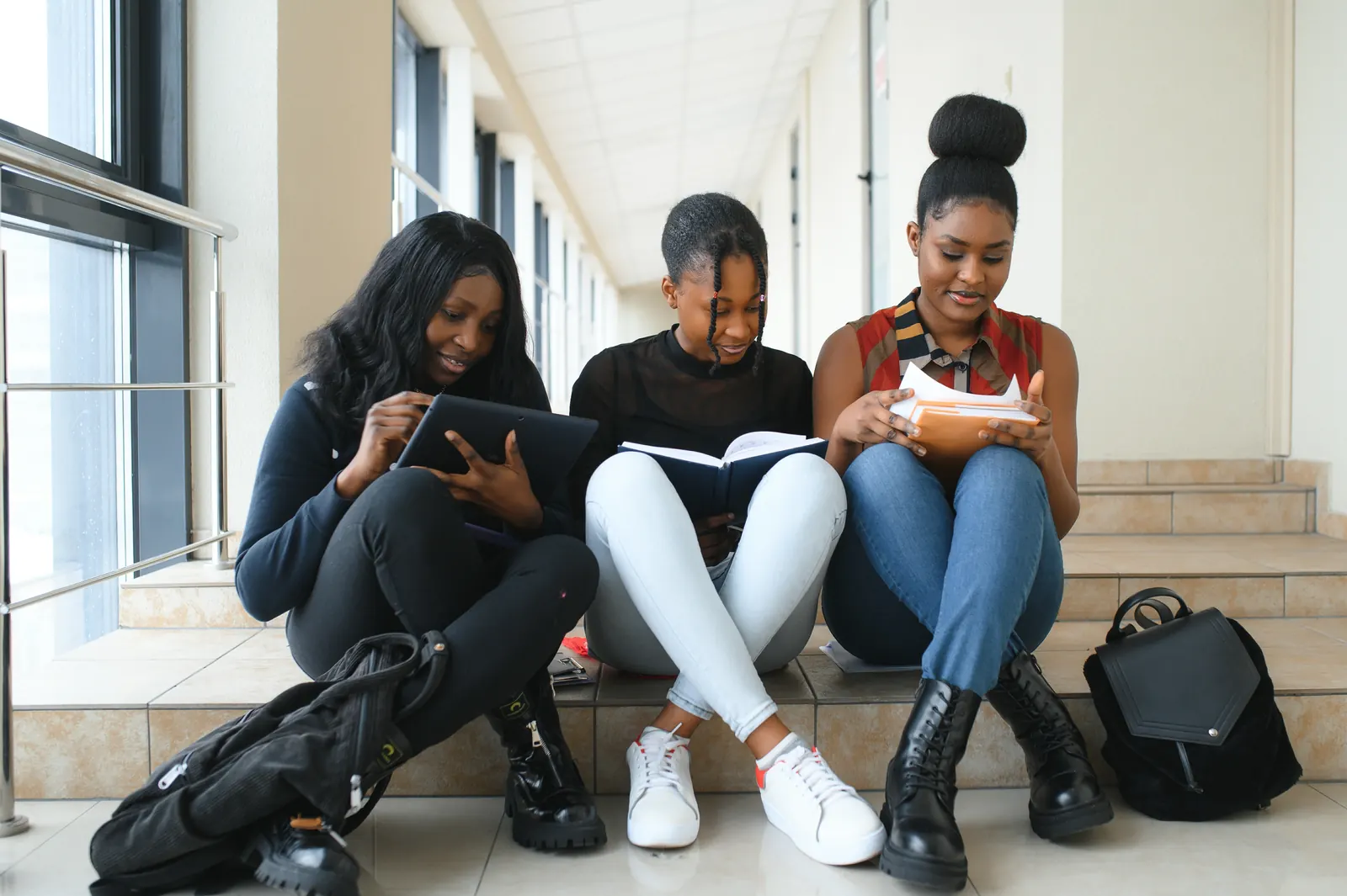 Trois étudiantes qui révisent ensemble avec tablette et livres